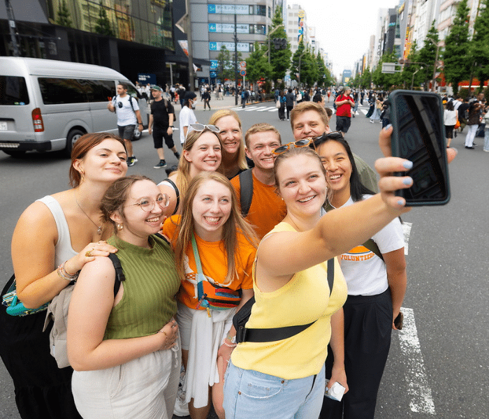 big group of students taking a selfie in the streets of Japan