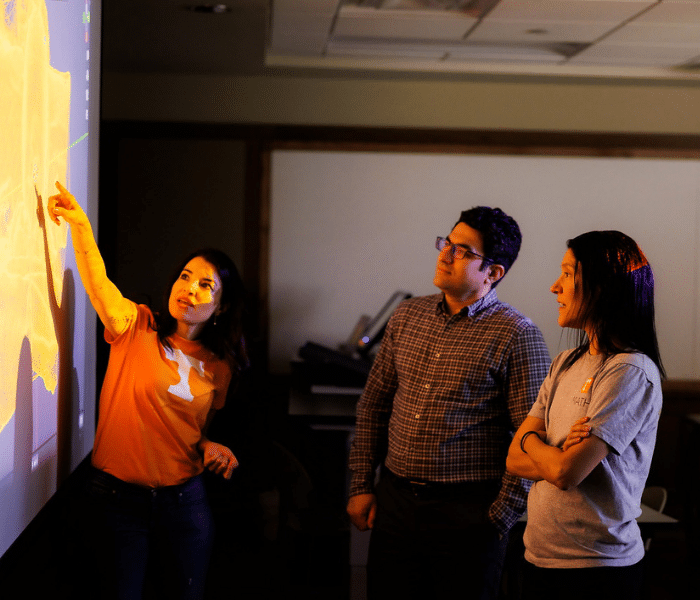Three scholars looking at a white board