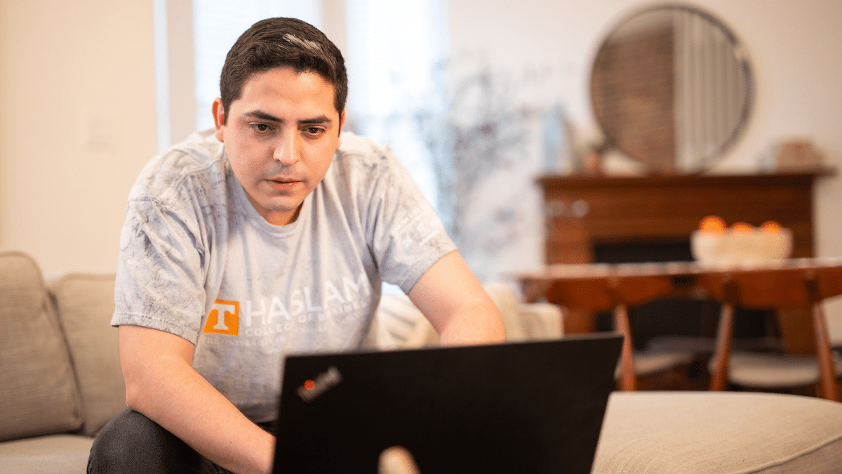 Man on a living room looking at his laptop.