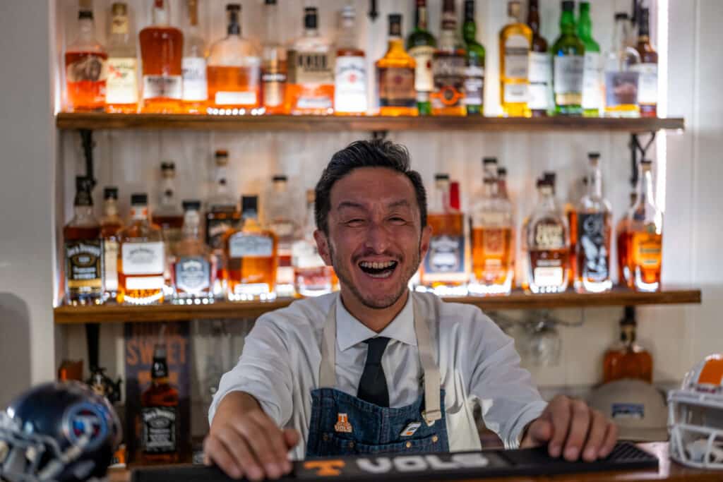 A man smiles behind a bar.